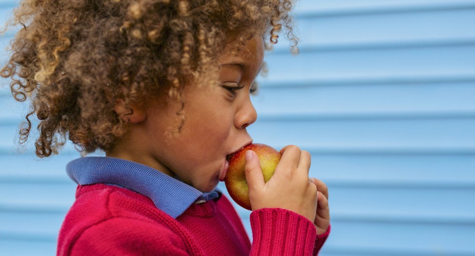Menino negro comendo maçã