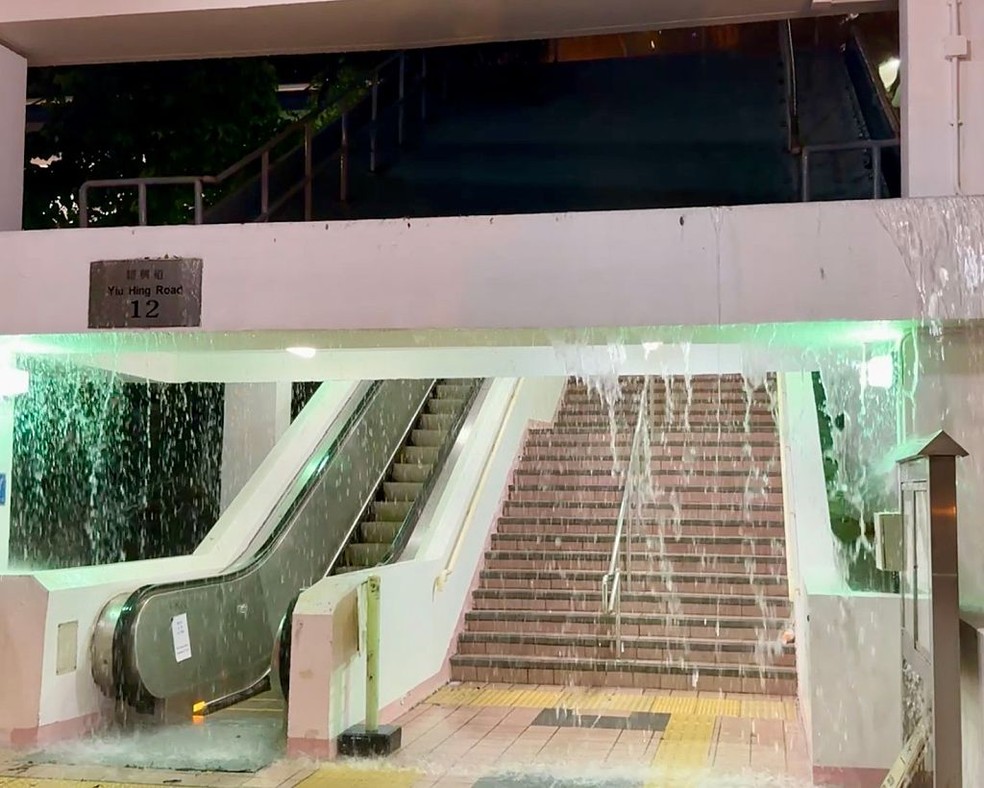 "Cachoeira" de chuva cai da entrada de uma escada rolante no Yiu Tung Estate, conjunto habitacional público em 5 de agosto de 2025 em Hong Kong, China. — Foto: Getty Images