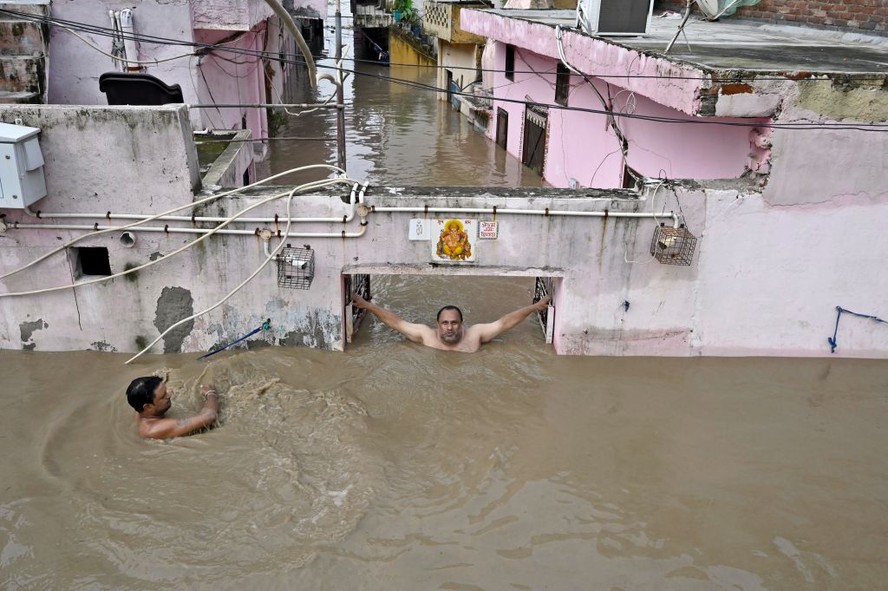 Moradores vistos em suas casas inundadas devido a fortes chuvas na região de Nova Délhi, na Índia