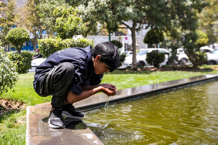Um menino se refresca em uma fonte durante uma onda de calor em Teerã, no Irã