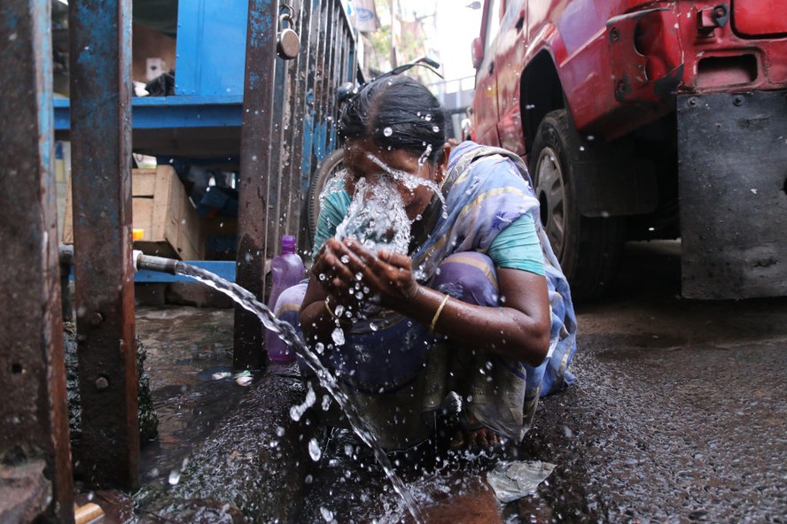 Mulher joga água no rosto para se refrescar durante onda de calor na Índia