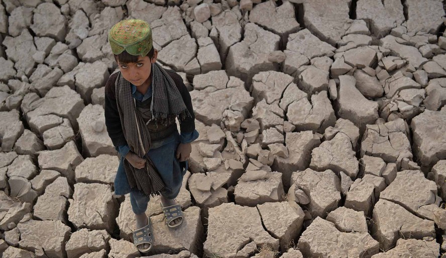 Criança em pé em terra seca na província de Badghis, no Afeganistão.