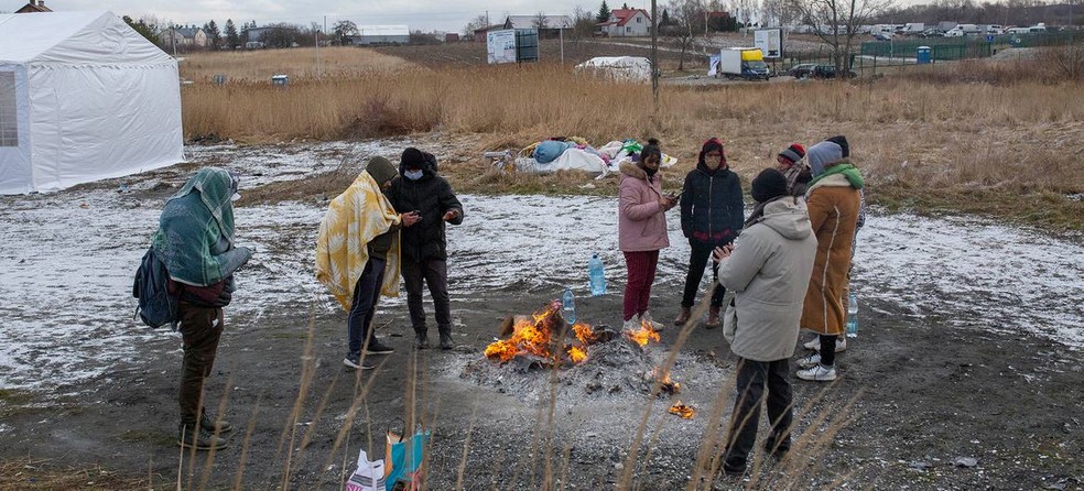 Refugiados da Ucrânia se aquecem em fogueira após cruzarem a fronteira para a Polônia em Medyka — Foto: Valerio Muscella / Acnur