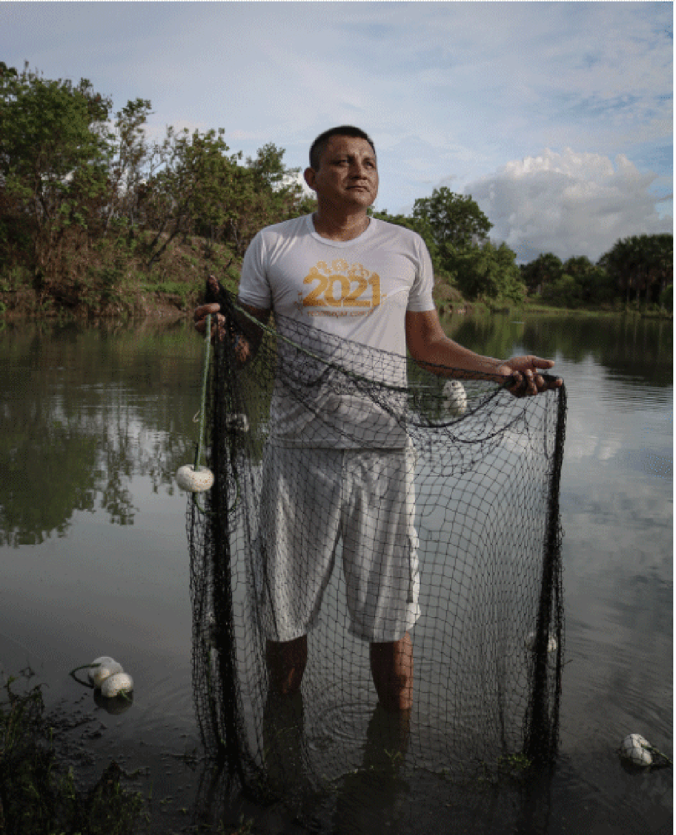 Deodato holds the fishing net inside the tank.  — Photo: Amanda Magnani