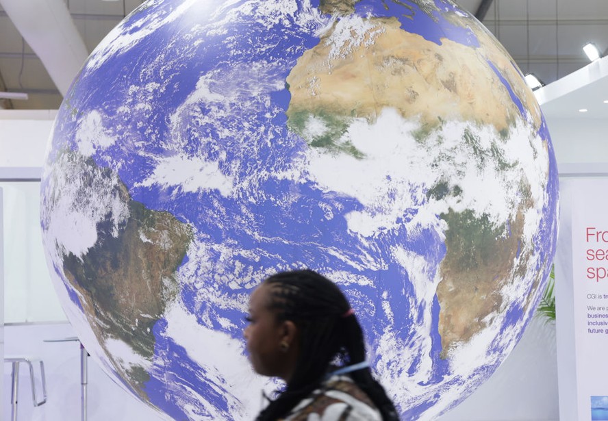 Uma participante da conferência passa por uma representação giratória do Planeta Terra durante a COP27