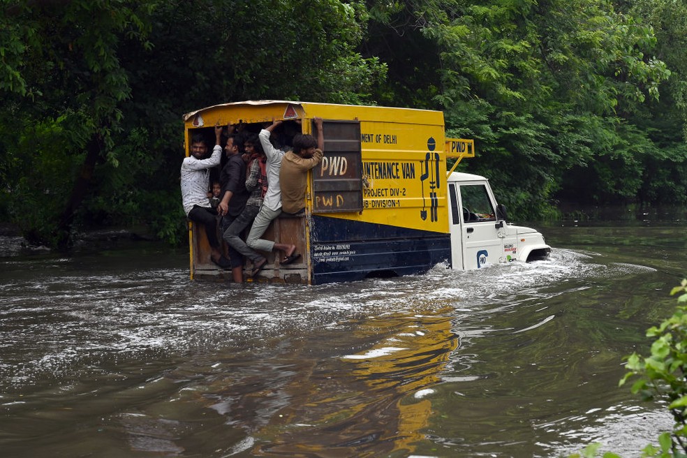 Um veículo transportando pessoas atravessa uma rua inundada em Nova Deli, na Índia, em 13 de julho de 2023 — Foto: Getty Images