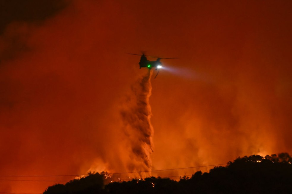 Helicóptero de combate a incêndio jogam água sobre as chamas no "Incêndio Palisades" em Los Angeles. — Foto: Tayfun Coskun/Anadolu via Getty Images