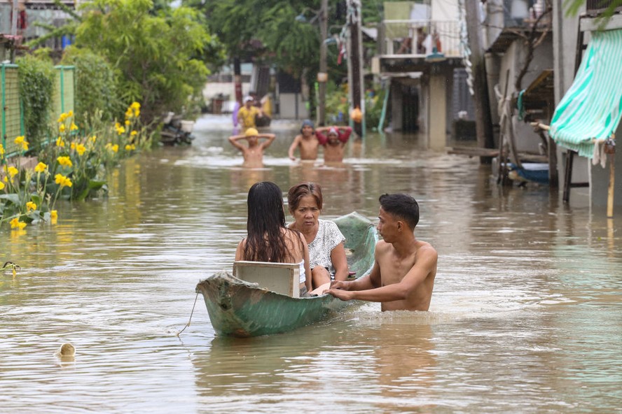 Moradores andam de barco para fugir de enchentes causadas pelas chuvas torrenciais do tufão Doksuri nas Filipinas
