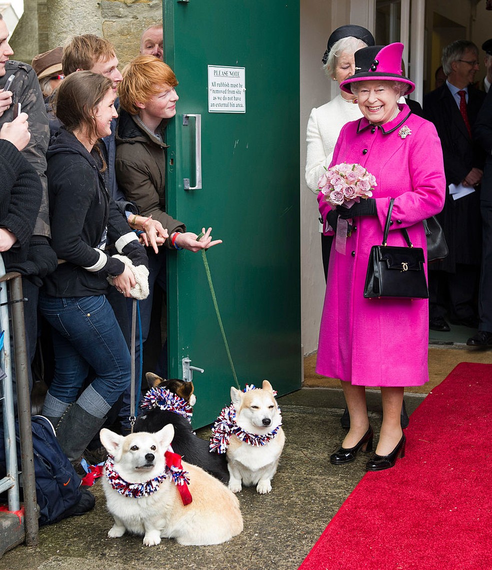 Rainha Elisabeth II posa ao lado de dois jovens com corgis durante evento oficial — Foto: Getty Images
