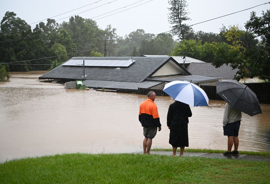 Moradores observam uma casa inundada pela enchente em Brisbane, na Austrália