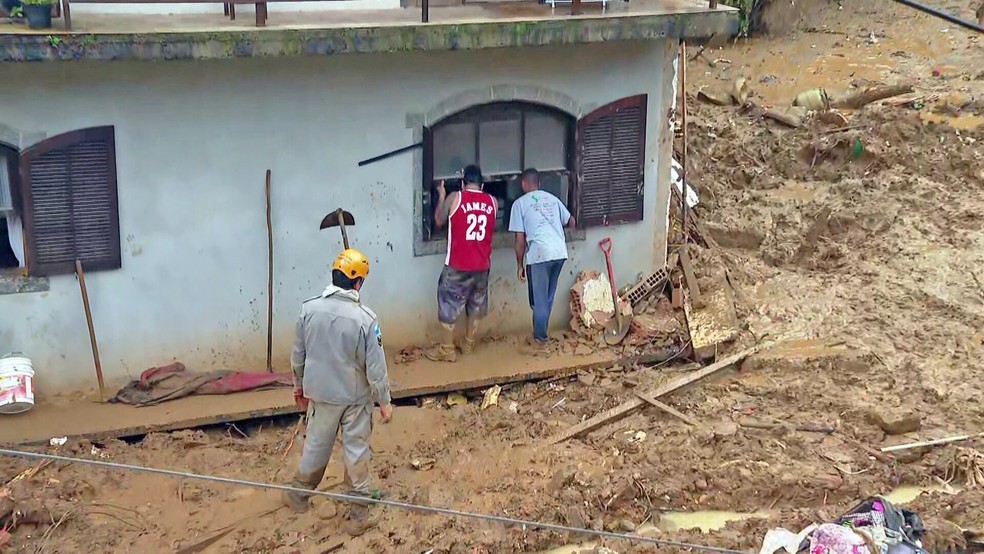 Socorristas buscam vítimas na janela do segundo andar de uma construção — o primeiro foi soterrado — Foto: Reprodução/TV Globo 