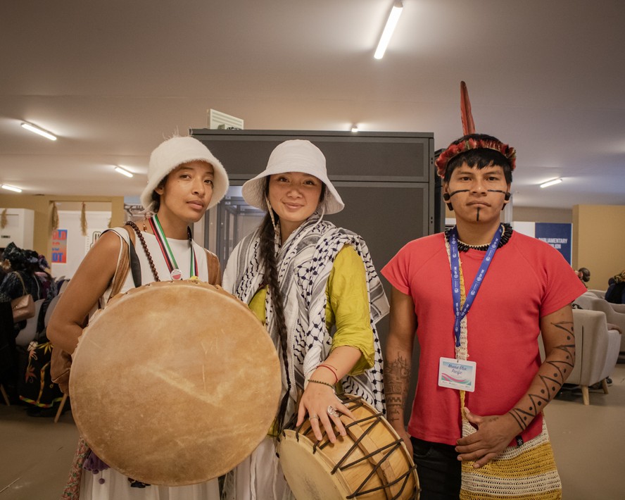 Mesiah (esquerda) com companheiros do seu povo, em frente ao pavilhão indígena