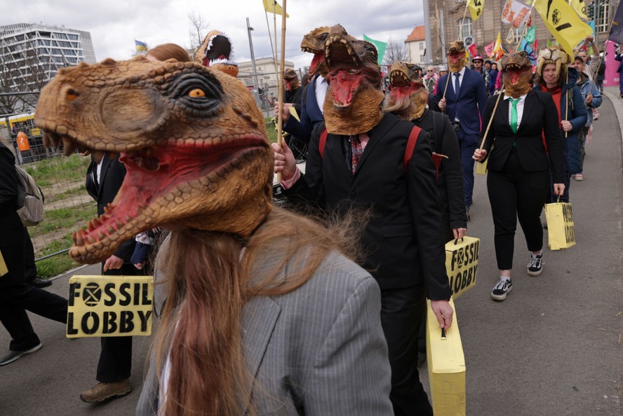 Ativistas vestidos como dinossauros do lobby dos combustíveis fósseis se reúnem no Portão de Brandemburgo durante uma manifestação em Berlim, Alemanha.